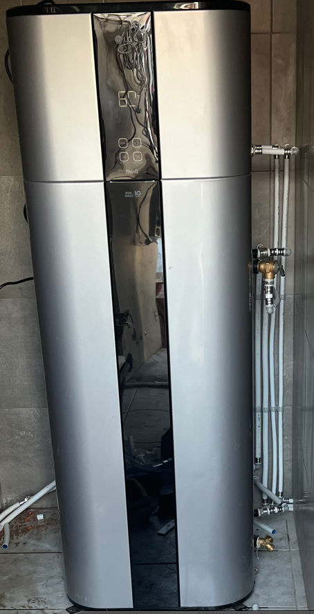 Nieuw geplaatste warmtepompboiler met aansluitleidingen in een betegelde technische ruimte