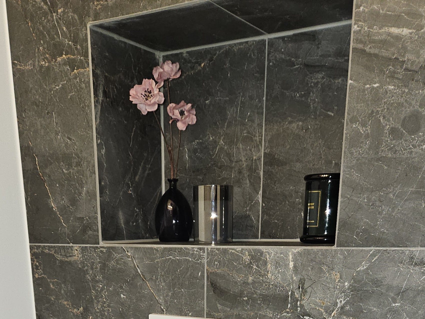 Nis in de tegelwand boven het toilet, met een vaasje bloemen
